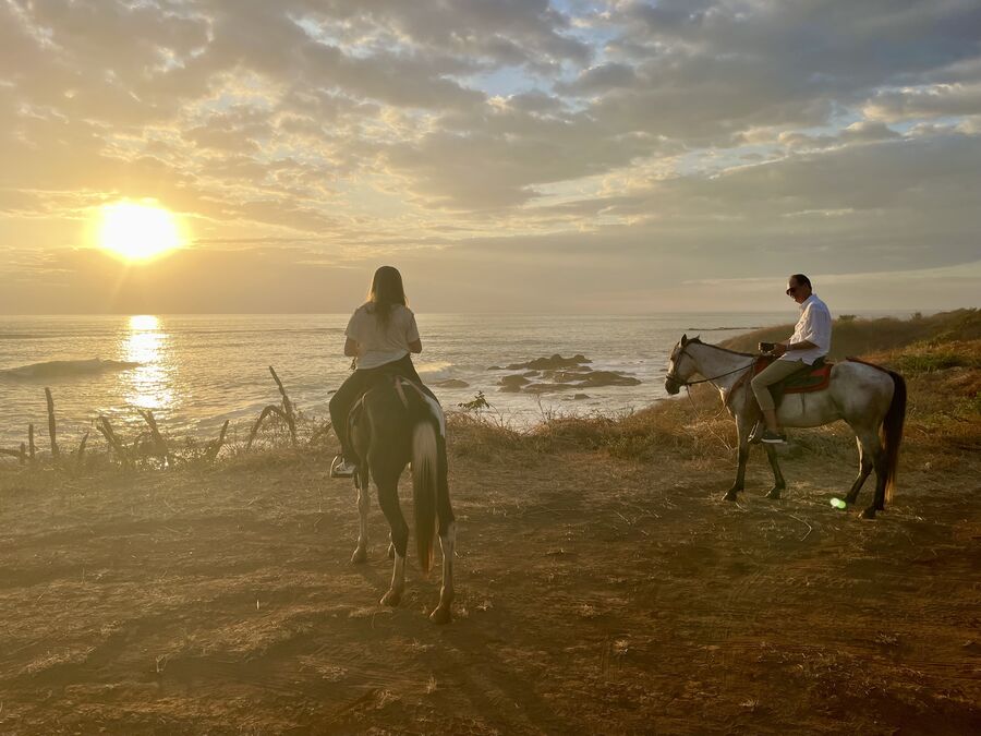 Riders overlooking the ocean at sunset on the coastal bluff